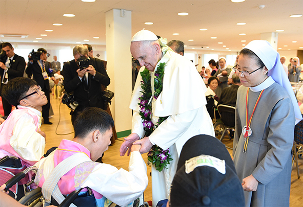 꽃동네를 방문한 프란치스코 교황이 장애우의 손을 잡아주고 있다.