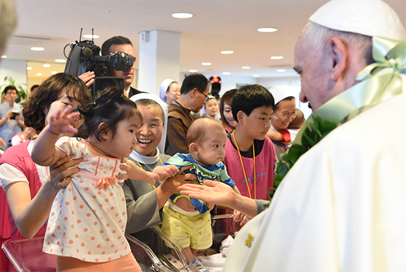 꽃동네를 방문한 교황이 시설 어린이에게 손을 내밀고 있다.