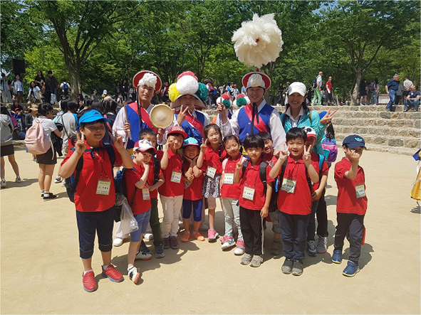 청룡초 어린이들이 용인 민속촌에서 풍물단원들과 기념촬영을 하고 있다.