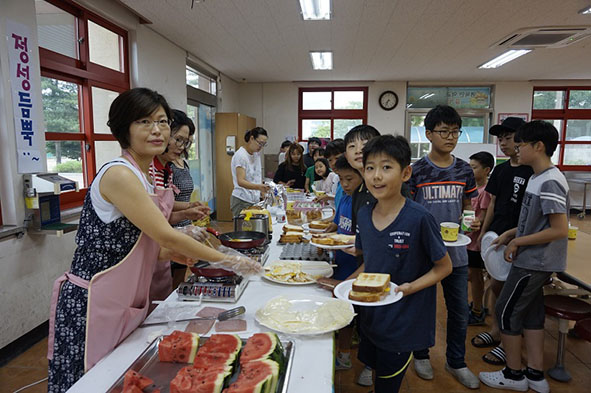 맹동초 교사와 가족들이 어린이들에게 음식을 제공하고 있다.