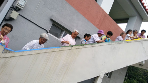 삼성 대사리 주민들이 마을회관 계단 난간을 칠하고 있다.