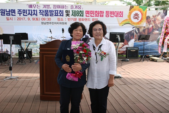 유복순씨가 국회의원 표창을 김윤희 군의원으로부터 대신 받고 있다.