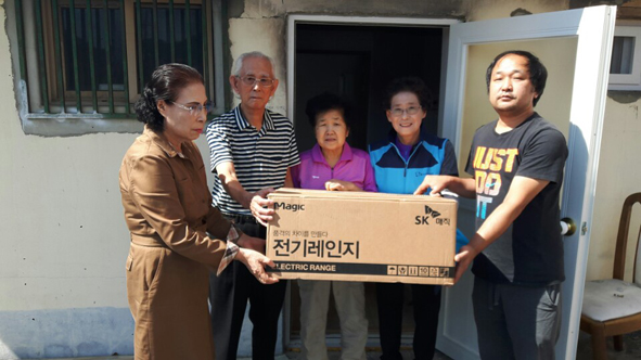 음성시니어클럽 9988시니어봉사회원들이 금왕읍 J씨 댁에 전기레인지를 전달하며 기념촬영을 하고 있다.