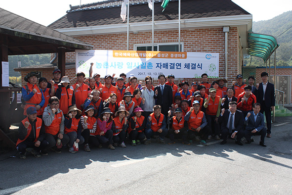 ▲한국체육산업개발 임직원들이 생1리 마을회관 앞에서 화이팅을 외치며 기념촬영을 하고 있다.