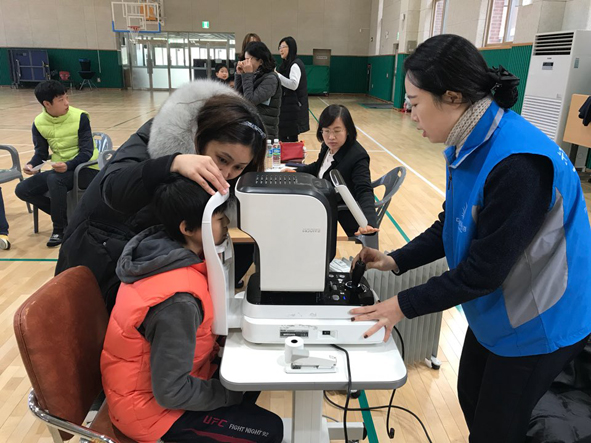 꽃동네학교에서 다비치안경 직원들이 학생들에게 시력검사를 실시하고 있다.