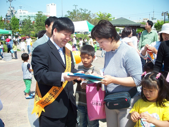 우성수 군의원이 어린이날 기념행사장에서 엄마에게 자녀교육에 대해 이야기를 나누고 있다.