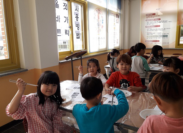 젓가락으로 콩을 짚어올리기 프로그램에 참여하고 있는 원남초 어린이들 모습.