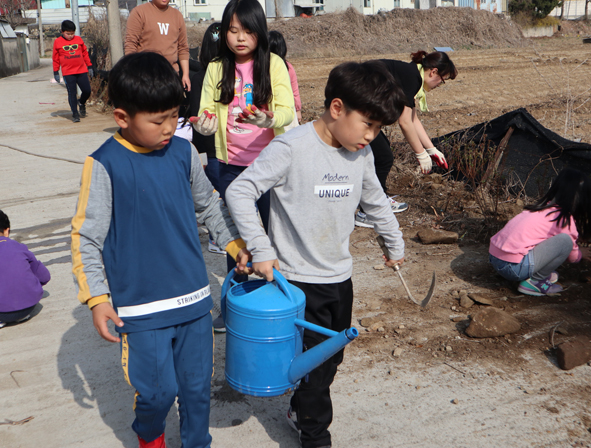청보리지역아동센터 아이들이 꽃을 심으며 물을 주고 있다.