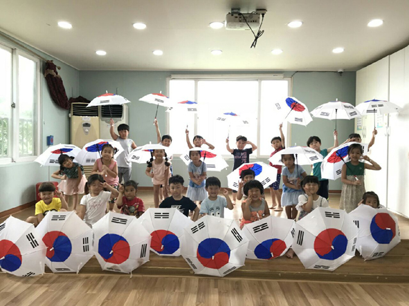 생극어린이집 어린이들이 대덕건설 김기명 대표가 나눠준 태극기 우산을 펴들고 기념촬영을 하고 있다.