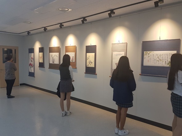 감곡도서관 전시실에 문인화 작품을 감상하고 있는 학생들 모습.