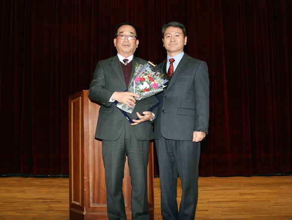 김영국 우정학원 이사장이 한현우 교장에게 축하 꽃다발을 전달하고 있다.