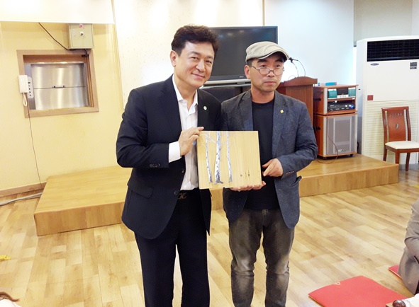 신재흥 청문관이 음성방문을 기념하는 의미로 자작나무 그림을 김병우 교육감에게 전달하고 있다.