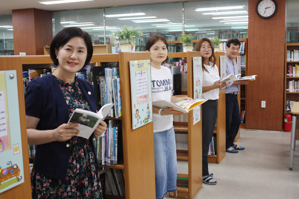 금왕교육도서관 정선옥 관장(사진 맨 앞)을 비롯한 직원들이 도서열람실에서 책을 들고 카메라를 응시하고 있다.