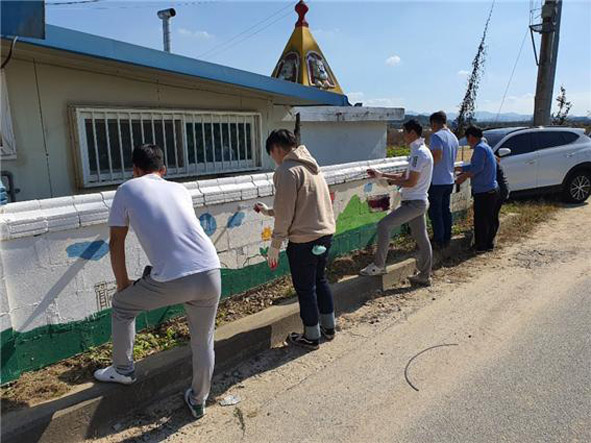 부윤지역아동센터 외벽 담장 도색을 하고 있는 (주)한독봉사단원들 모습.