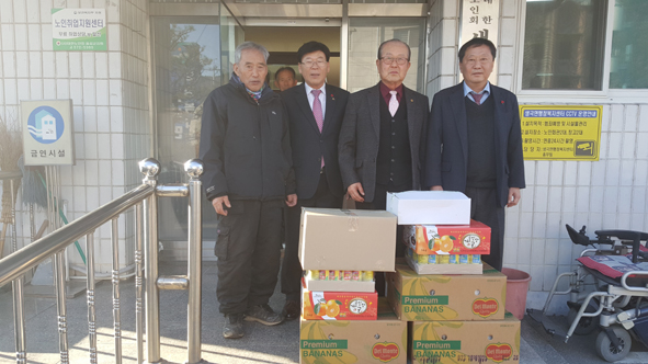 대덕건설 김기명 대표가 생극노인회에 식료품을 전달하며, 참석자들과 기념촬영을 하고 있다.