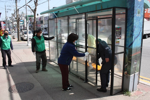▲금왕읍 직원들과 부녀회원들이 버스 승강장에서 방역활동을 펼치고 있다.