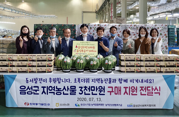 한국동서발전 관계자가 음성군 농특산물을 구매하며, 현장 참석자들과 기념촬영을 하고 있다.