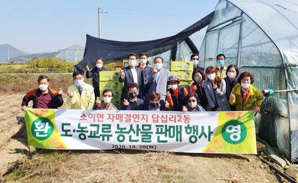 소이주민자치위와 서울 답십리2동 주민자치위가 도농협력을 이어가는 농산물 판매행사를 진행하며 기념촬영을 하고 있다.