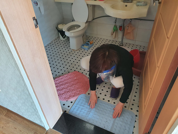 관내 어르신 가정 화장실에 미끄럼방지 매트를 설치하고 있는 모습.