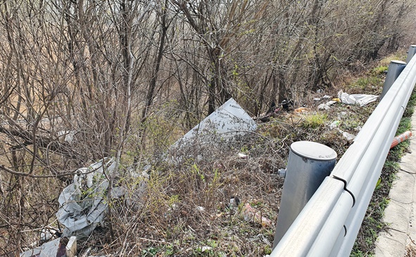 국도 37호선 가드레일 밖 언덕에 쓰레기가 방치돼 있다.