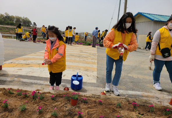 음성군자원봉사센터 온 가족봉사단 가족들이 꽃묘를 심고 있다.