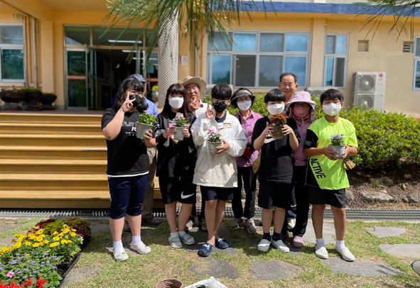 하당초 어린이들이 마을 주민들과 함께 화분 꽃심기 체험활동에 참여하며 기념촬영을 하고 있다.