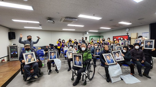 금빛라이온스클럽 회원들이 장애인복지관 소속 재가장애인들에게 추억의 사진을 전달하며 기념촬영을 하고 있다.
