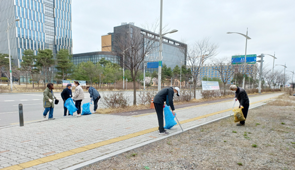 회원들이 한국소비자보호원 앞에서 쓰레기를 줍고 있다.