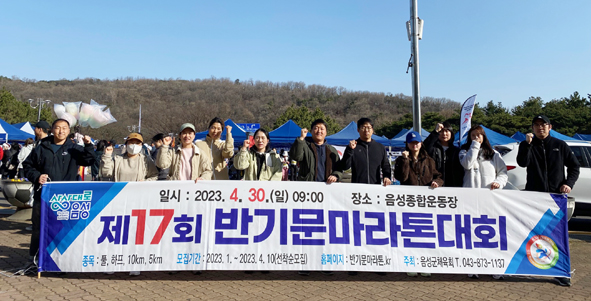 관계자들이 제17회 반기문마라톤대회 홍보현수막을 들고 기념촬영을 하고 있는 모습.
