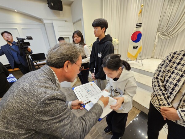 왼쪽 김형권 금왕읍기업인협의회장이 한 어린이에게 장학증서와 장학금을 전달하고 있다.  