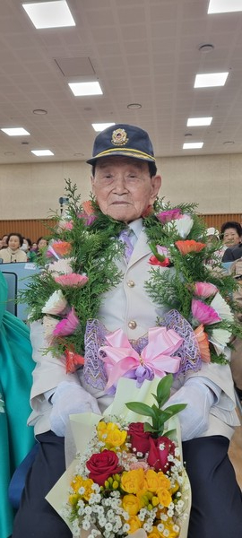 101세 한종상 할아버지가 꽃목걸이와 함께 백세 케익 앞에서 기념촬영하고 있다.